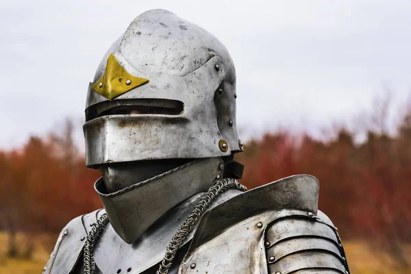 Knight in helmet and armour before battle on red forest background — Stock Photo, Image
