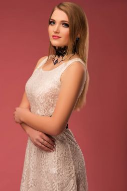 Pembe bir arka plan üzerinde beyaz elbiseli güzel mutlu bir genç kadın