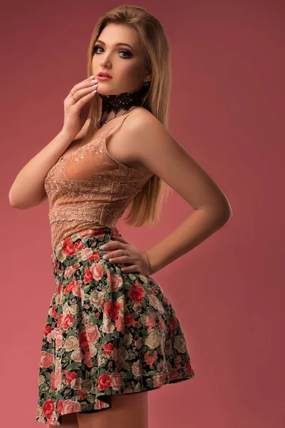 Fashion photo of a beautiful young woman in a pretty clothes with flowers posing on the pink background. Fashion photo — Stock Photo, Image