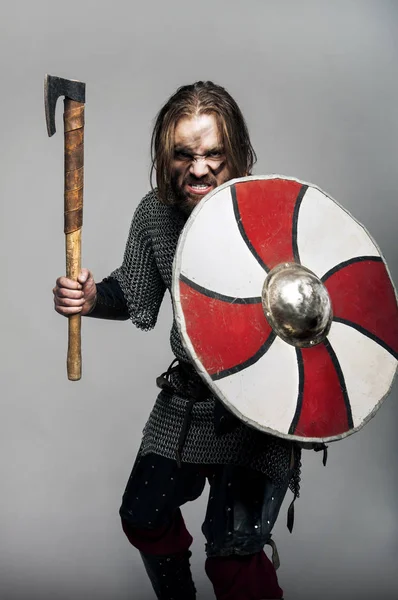 Viking schreeuwen met zijn bijl en schild op de grijze achtergrond — Stockfoto