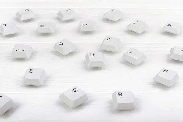 Keyboard keys isolated. White keyboard keys on white wooden background. Top view. Close up