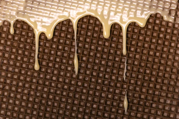 Waffle coberto com leite condensado close-up. Chocolate branco quente se espalha na bolacha. Comida saborosa — Fotografia de Stock