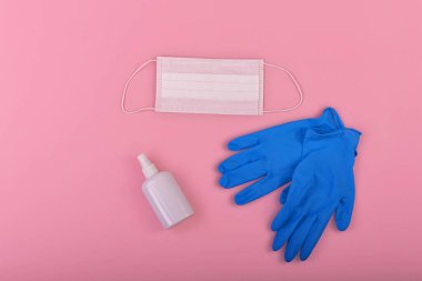 Tıbbi maskeli pembe tıbbi geçmiş, antiseptik ve mavi laboratuvar eldivenleri. Virüs koruma ekipmanları. Tehlikeli Asya ncov coronavirüsü.