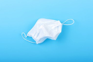 Üzerinde tıbbi maske bulunan mavi bir arka plan. Virüs koruma ekipmanları. Tehlikeli Asya ncov coronavirüsü.