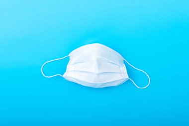 Üzerinde tıbbi maske bulunan mavi bir arka plan. Virüs koruma ekipmanları. Tehlikeli Asya ncov coronavirüsü.