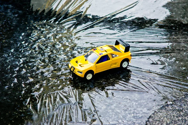 A toy yellow utility vehicle resting on an ice plate.