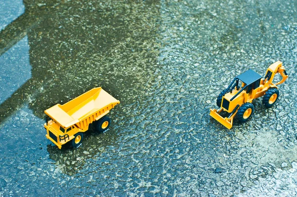 A cement floor truck with a little water and a folk toy car looking down from above.