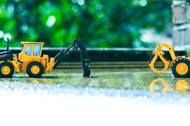 İki sarı oyuncak forklines bahar yağmur sonrası biraz su ile bahçede oynuyorlar.