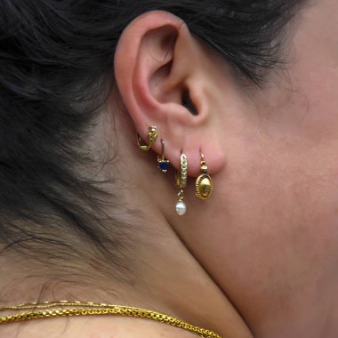 golden earrings and chains in close-up in contrast to black hair and clear skin on gypsy lady clipart