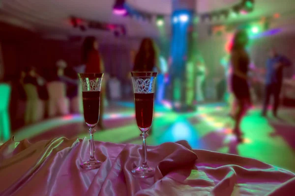 two red wine glasses on foreground and blur abstract at night club party in restaurant on background