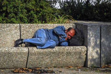 Paris, Fransa - 23 Eylül 2008: Evsiz uyumayan şehir parkı içinde taş bir bankta adamdır. sokak fotoğrafçılığı  