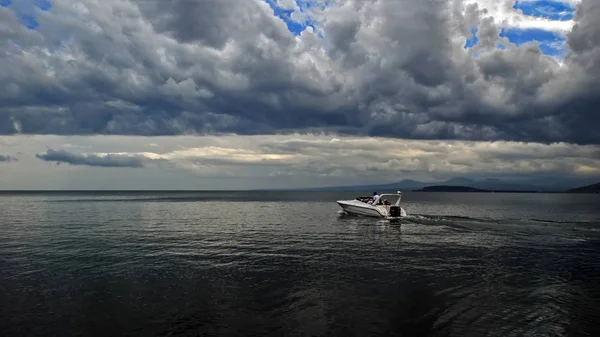 Férfi fehér hajó, a Szeván-tó, drámai felhős ég, Örményország — Stock Fotó