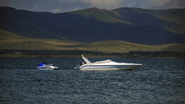 Hajó és jet-ski a Szeván-tó partján háttér mellett örmény — Stock Fotó