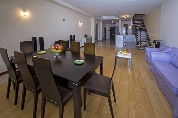 Ein modernes Apartment-Wohnzimmer mit Holztisch und Stühlen. Luxus-Wohnung mit stilvollem, modernem Interieur — Stockfoto