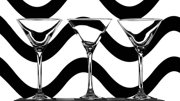 Három elegáns üres koktél szemüveg absztrakt fekete-fehér hullámos háttér — Stock Fotó