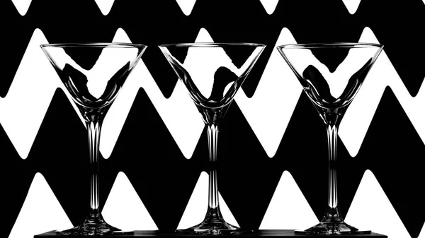 Tres elegantes vasos de cóctel vacíos sobre fondo abstracto en blanco y negro —  Fotos de Stock