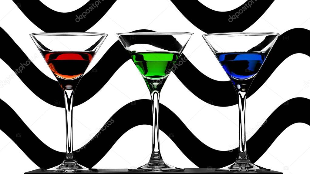 three elegant cocktail glasses with red, green and blue liquors on abstract wavy background with black and white waves