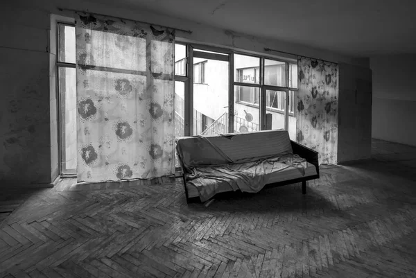 Quarto desarrumado abandonado. velho sofá numa casa abandonada. fotografia em preto e branco — Fotografia de Stock