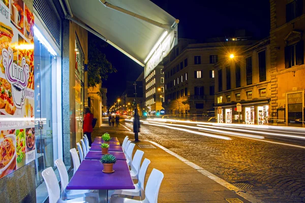 Rome, Italie - 16 novembre 2016 : chaises blanches vides et tables violettes avec des plantes vertes par restaurant dans la rue via Nazionale illuminées la nuit. Beau paysage urbain nocturne adapté aux milieux . — Photo