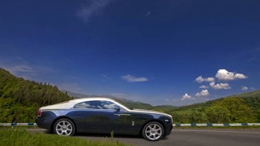 Egnatia Odos Motorway, Greece - July 10, 2014: blue and silver Rolls-Royce Wraith coupe on picturesque mountain road clipart