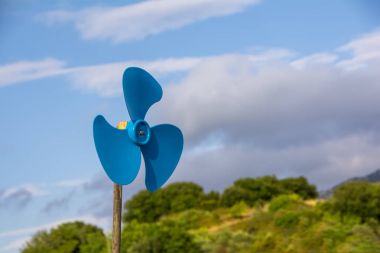 mavi plastik pervane doğa ile tepe üzerinde yeşil orman ve mavi gökyüzü bulutlu arka plan bulanık karşı. Seçici odak