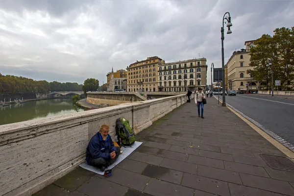 Roma, 17 novembre 2016: un senzatetto sorridente siede sul ponte di Ponte Cavour e raccoglie elemosine. Fotografia di strada con persona amichevole ottimista — Foto Stock