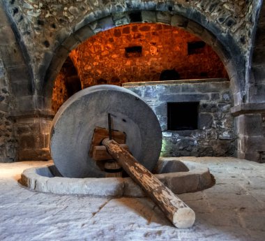big stone millstone of ancient press in The Tatev Oil Mill at Tatev Monastery, Armenia, 9th century clipart