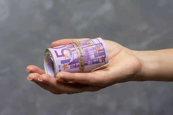 Makro-Detail einer Rolle Eurowährung (Euro) mit 500-Euro-Banknoten in einer Frauenhand auf grauem Hintergrund — Stockfoto