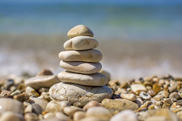 Stack of zen stones on beach. Pyramid of stones on the beach. Zen meditation background - balanced stones stack close up. Blurred background with sea