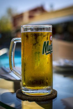 Corfu, Yunanistan - 26 Ağustos 2017: Mythos light bira arka plan bulanık önünde soğuk bir bardak