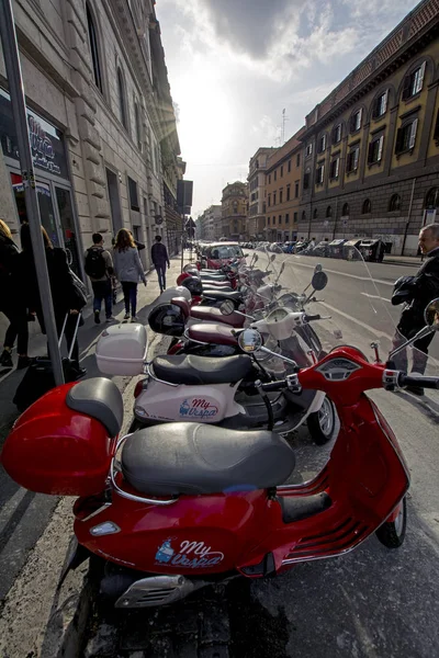 Rome, Italië - 18 November 2016: een rij geparkeerde scooters op een stad weg met heldere rode Vespa scooter op voorgrond — Stockfoto