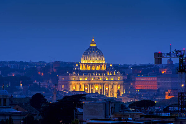 Beautiful night cityscape from the roof in Rome, Italy with illuminated dome of the Basilica of Saint Peter in background