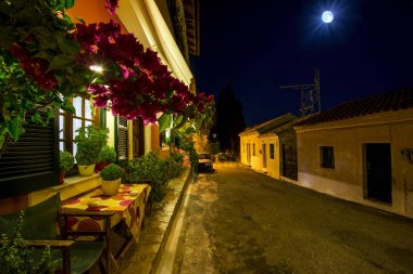 gece cityscape dar sokakları ve antika evler Corfu Island, Yunanistan ile eski Akdeniz Köyü Karousades. Güzel çiçekler ile küçük kafe