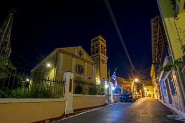gece cityscape eski Akdeniz Köyü Karousades Ortodoks Kilisesi ve antika evleri, Corfu, Yunanistan ile dar sokak arabalar