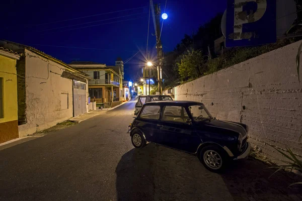 Karousades 2017年8月31日 夜城市景观老地中海村庄与海军蓝色奥斯汀微型库珀1000在狭窄的街道与古色古香的房子在满月之下 — 图库照片