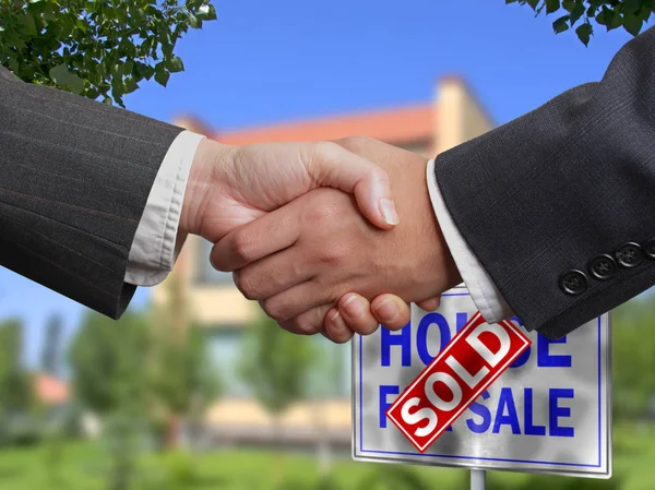 Home For Sale Real Estate Sign in Front of Beautiful New House Sold. Blurred background. Handshake business deal. Communication commerce real estate. Corporate concept