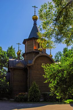 Sevimli küçük eski ahşap Ortodoks Kilisesi sun, Moskova, Rusya tarafından yaktı yeşil ağaçların arasından görülür