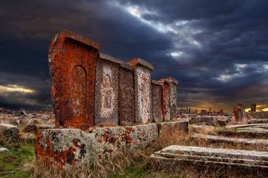 Khachkars yosun ve Noratus tarihi mezarlık Ermenistan, liken kaplı olarak bilinen antik mezar taşları yakınındaki güzel dramatik günbatımı gökyüzü altında Sevan Gölü. 10 yüzyıla