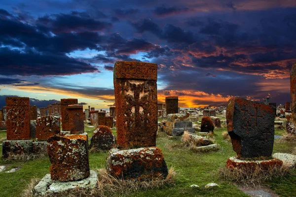 Ancient tombstones known as Khachkars covered with moss and lichen in the Historical cemetery of Noratus in Armenia, near the Lake Sevan under the beautiful dramatic sunset sky. 10th century