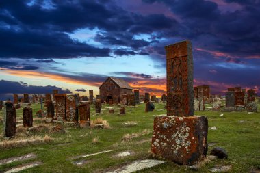 Khachkars bilinen antik mezar taşları ve yosun ve Noratus tarihi mezarlık Ermenistan, liken kaplı Şapel yakınındaki güzel dramatik günbatımı gökyüzü altında Sevan Gölü. 10 yüzyıla