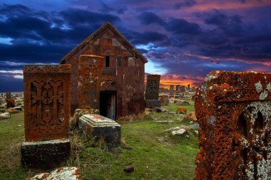 Khachkars bilinen antik mezar taşları ve yosun ve Noratus tarihi mezarlık Ermenistan, liken kaplı Şapel yakınındaki güzel dramatik günbatımı gökyüzü altında Sevan Gölü. 10 yüzyıla