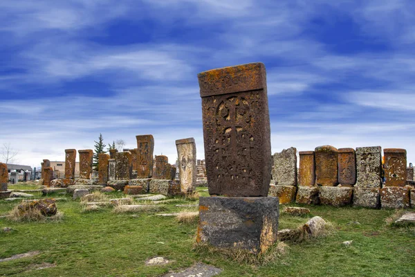 Ancient tombstones known as Khachkars covered with moss and lichen in the Historical cemetery of Noratus in Armenia, near the Lake Sevan under the beautiful blue sky. 10th century