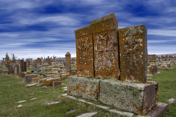 Ancient tombstones known as Khachkars covered with moss and lichen in the Historical cemetery of Noratus in Armenia, near the Lake Sevan under the beautiful blue sky. 10th century