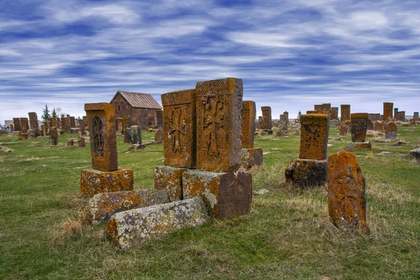 Ancient tombstones known as Khachkars and chapel covered with moss and lichen in the Historical cemetery of Noratus in Armenia, near the Lake Sevan under beautiful blue sky. 10th century