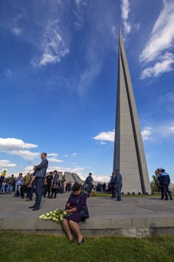 Yerevan, Ermenistan - 24 Nisan 2018: beyaz çiçekli kadın Tsitsernakaberd Ermeni Soykırımı Anıtı, 1915 Ermeni Soykırımı yıldönümünde karşısında oturur