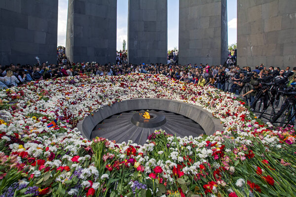 Yerevan, Armenia - April 24, 2018: Armenians laying flowers at the eternal flame in the center of the twelve slabs  of Armenian Genocide memorial on anniversary of Armenian Genocide of 1915