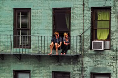 New York City, Amerika Birleşik Devletleri - 10 Ağustos 2012: Genç bir çift balkon eski tuğla evinde kendi evinde oturur