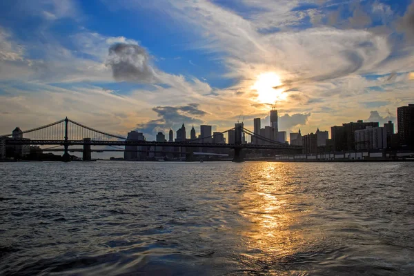 有名なマンハッタンとブルックリン橋 バック グラウンドでマンハッタンのダウンタウンの金融街とニューヨーク市 アメリカ合衆国 イースト川と美しい夕日の反射 — ストック写真