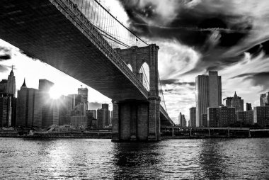 New York City, ABD finansal bölge, şehir Manhattan arka planda ile ünlü Brooklyn Köprüsü. Doğu Nehri ve güzel günbatımı yansıması. Siyah ve beyaz kontrast Fotoğrafçılık, düşük açılı görünüş