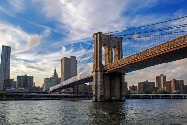 New York City, ABD finansal bölge, şehir Manhattan arka planda ile ünlü Brooklyn Köprüsü. Doğu Nehri ve güzel günbatımı yansıması. Düşük açılı görünüş